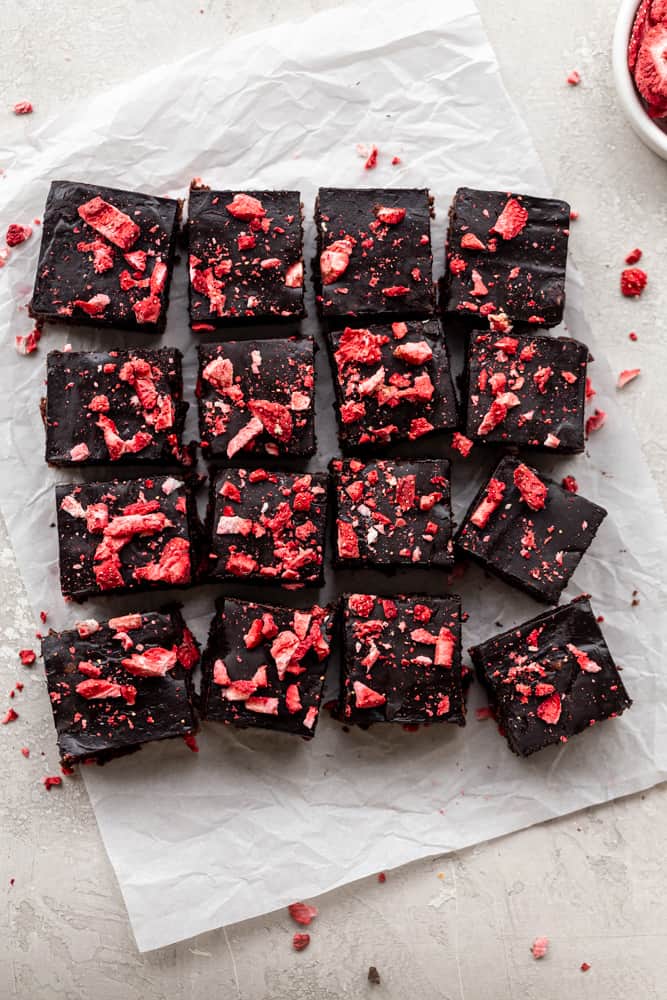 Strawberry brownies cut into pieces on a piece of parchment paper