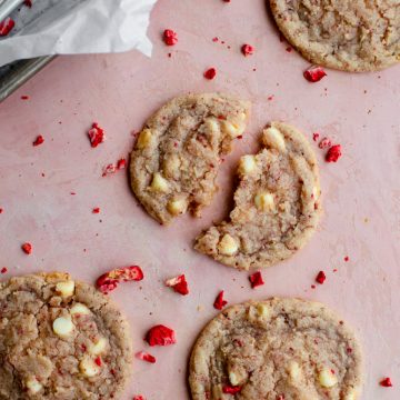 strawberry cookies broken apart on a pink surface