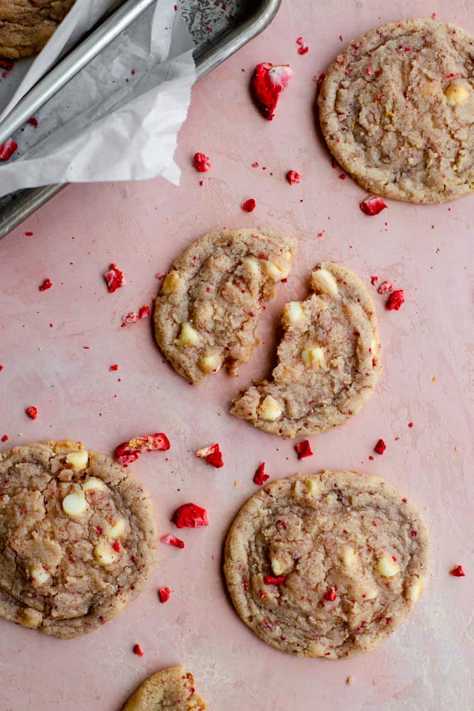 Strawberry cookies broken apart on a pink surface