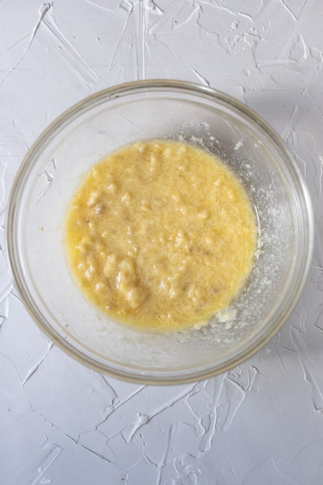 Wet banana muffin batter in a glass bowl