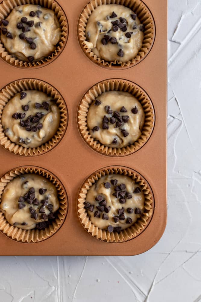 A muffin tin filled with chocolate chip banana muffin batter