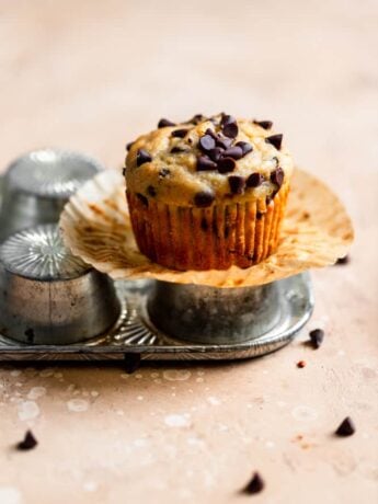 A chocolate chip banana muffin sitting on top of an overturned muffin pan