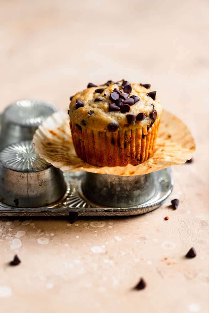 A chocolate chip banana muffin sitting on top of an overturned muffin pan