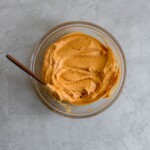 A pumpkin and cream cheese mixture in a glass bowl on a gray surface