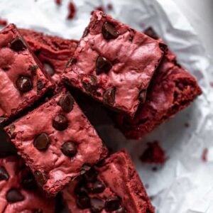 4 Red velvet brownies layered on top of each other on a piece of crinkled parchment paper