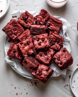 Red velvet brownies layered on a plate covered in parchment paper
