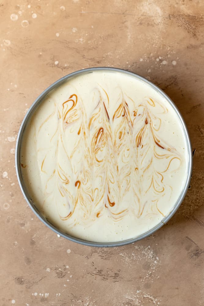 Cheesecake batter swirled with caramel in a springform pan