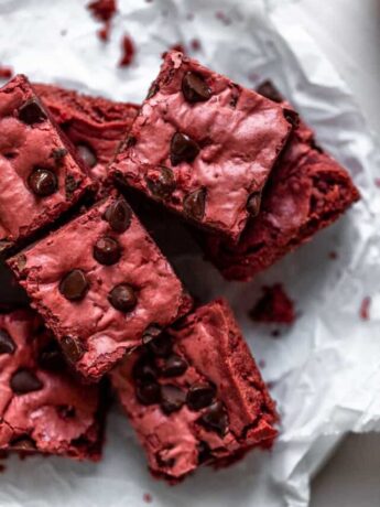 4 Red velvet brownies layered on top of each other on a piece of crinkled parchment paper