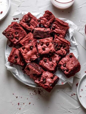 Red velvet brownies layered on a plate covered in parchment paper