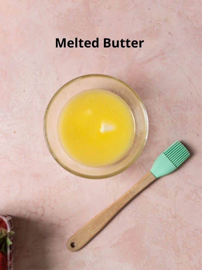 melted butter in a glass bowl on a pink surface