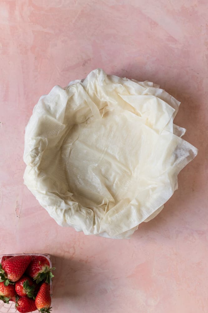 An entire package of phyllo dough laid over a springform pan