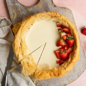 A slice cut into a strawberry cheesecake that has a phyllo dough crust