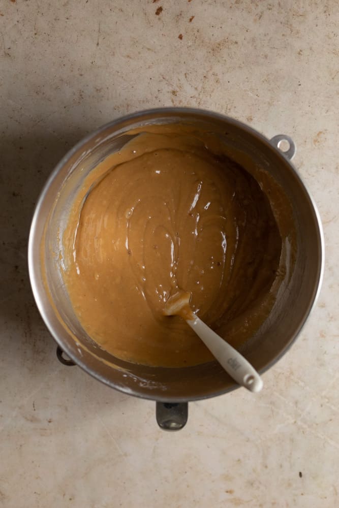 Cookie butter cake batter in a mixing bowl with a spatula inside