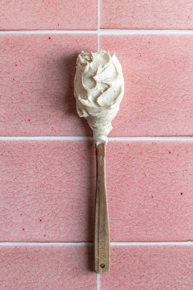 Espresso buttercream on a spatula laying on a pink tiled surface