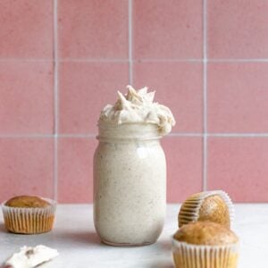 Espresso buttercream in a mason jar next to 3 unfrosted cupcakes