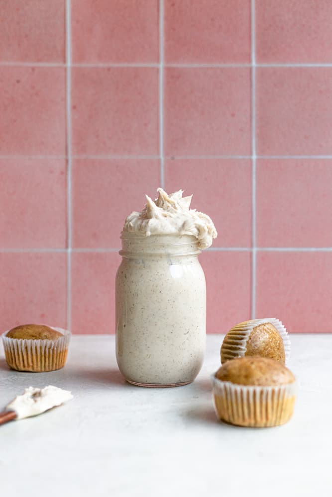 Espresso buttercream in a mason jar next to 3 unfrosted cupcakes