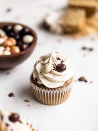 Espresso cupcakes on a white surface next to chocolate covered espresso beans in a bowl