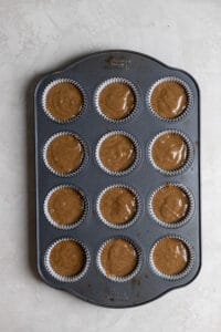 Cupcake batter in a 12 cup muffin tin on a grey surface