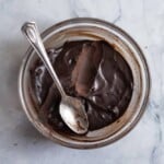 Hardened chocolate ganache ready to fill cupcakes in a glass bowl with spoon