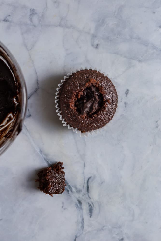 a chocolate cupcake stuffed with ganache with the top of it on the side. 