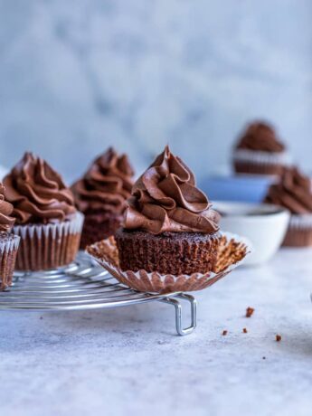 Chocolate filled cupcakes on a cooling rack with its wrapper undone
