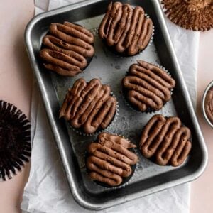 6 chocolate frosted chocolate cupcakes on a small sheet tray