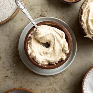 Caramel buttercream swirled in a wooden bowl with a spoon sticking out