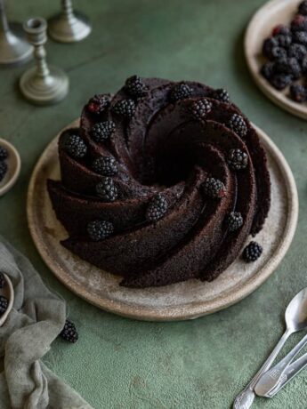 A chocolate bundt cake with blackberries garnished on top.