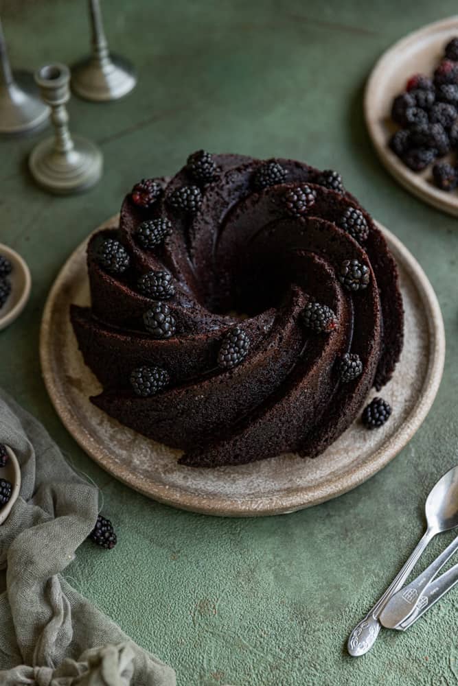 A chocolate bundt cake with blackberries garnished on top.