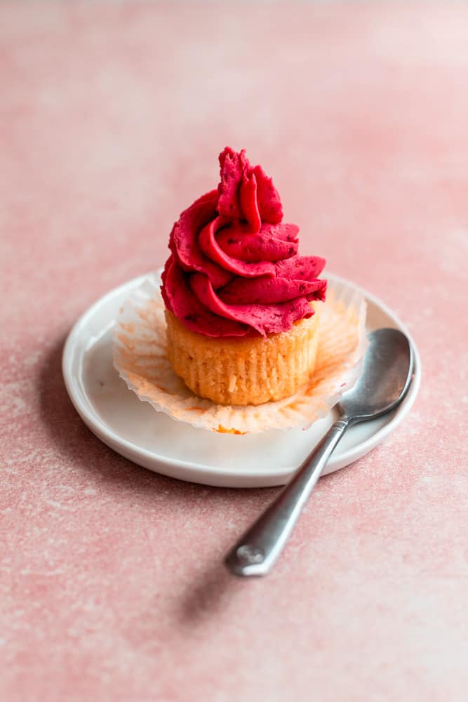 Vanilla cupcake with raspberry frosting on a white plate
