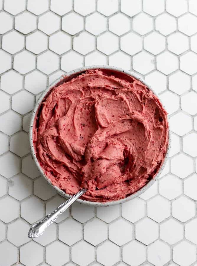 Strawberry buttercream frosting in a bowl on a white background