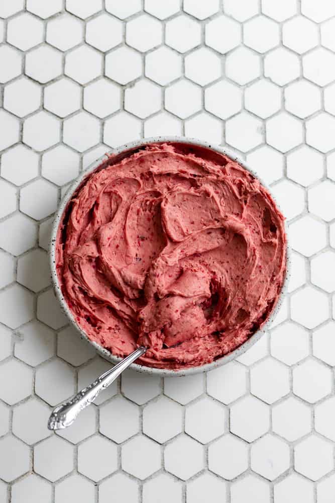 Strawberry buttercream frosting in a bowl on a white background
