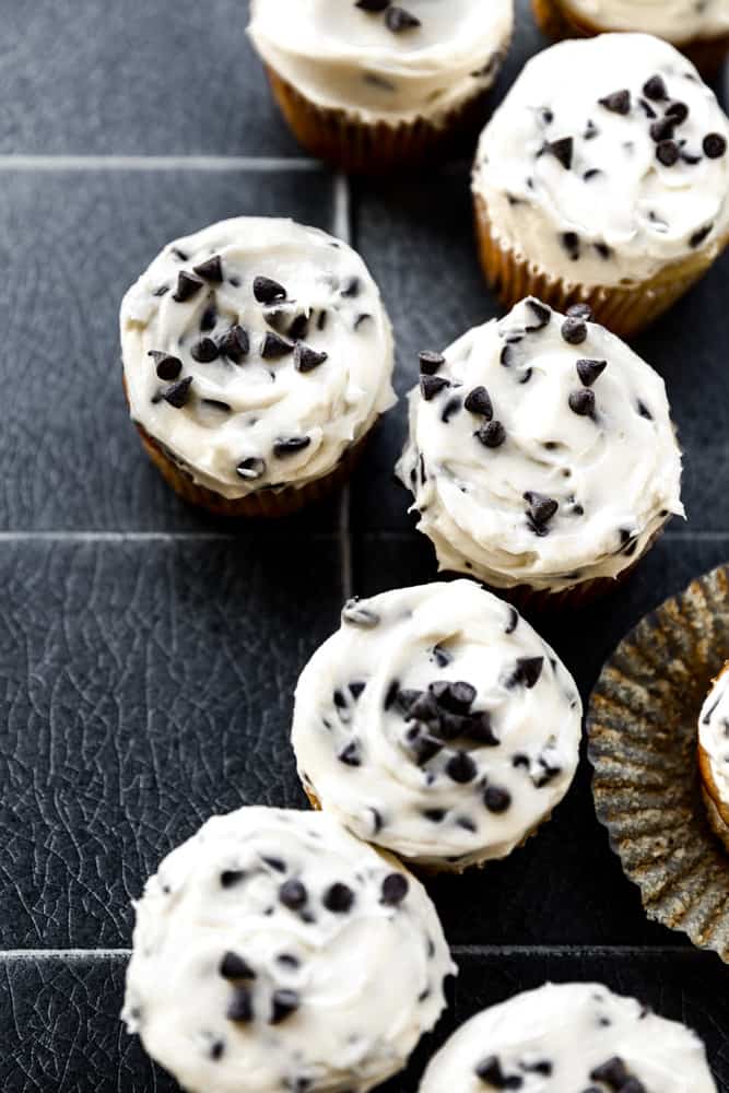 Chocolate chip cupcakes on a black tiled surface.