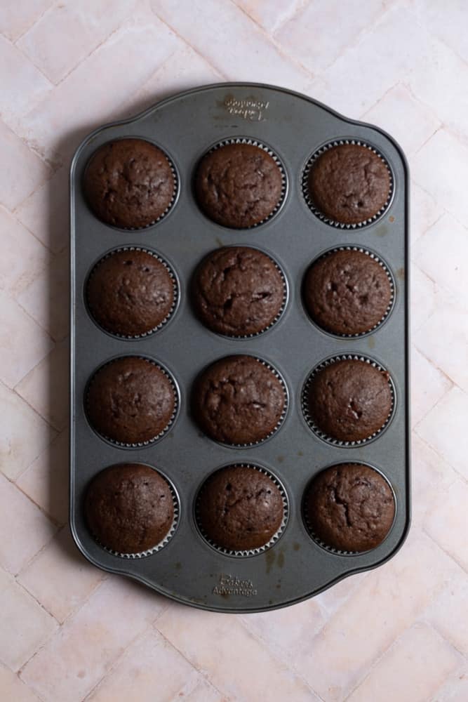 A muffin tin filled with baked chocolate cupcakes