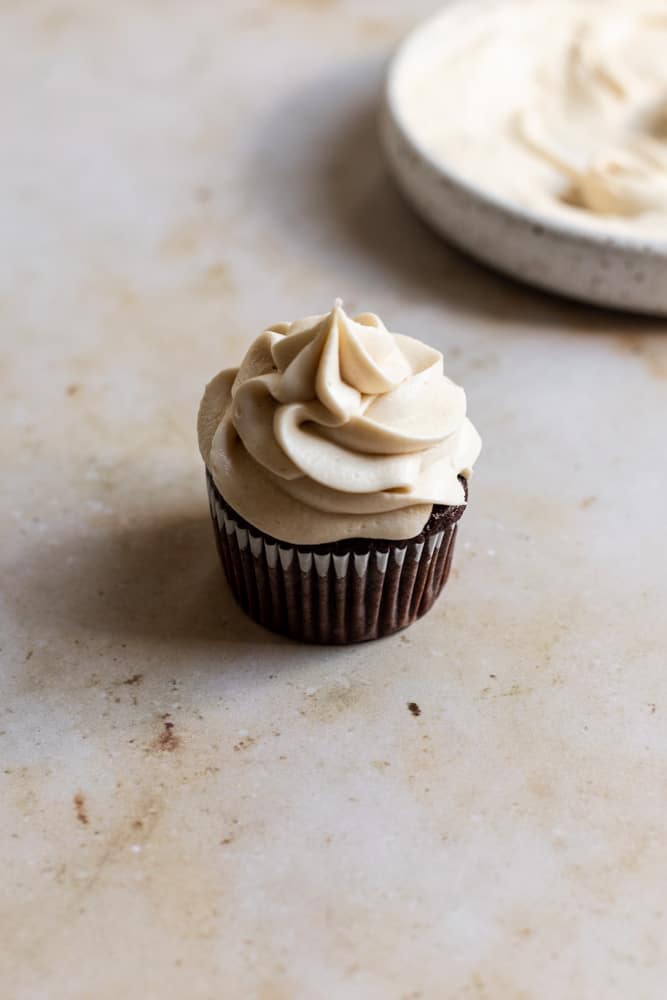 A chocolate cupcake topped with brown sugar buttercream.