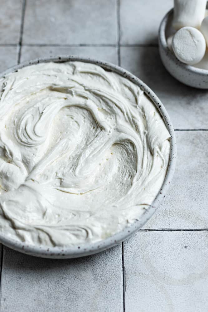 Marshmallow frosting in a bowl on a gray surface.