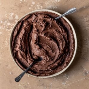 Chocolate buttercream swirled in a bowl with two spoons inside.