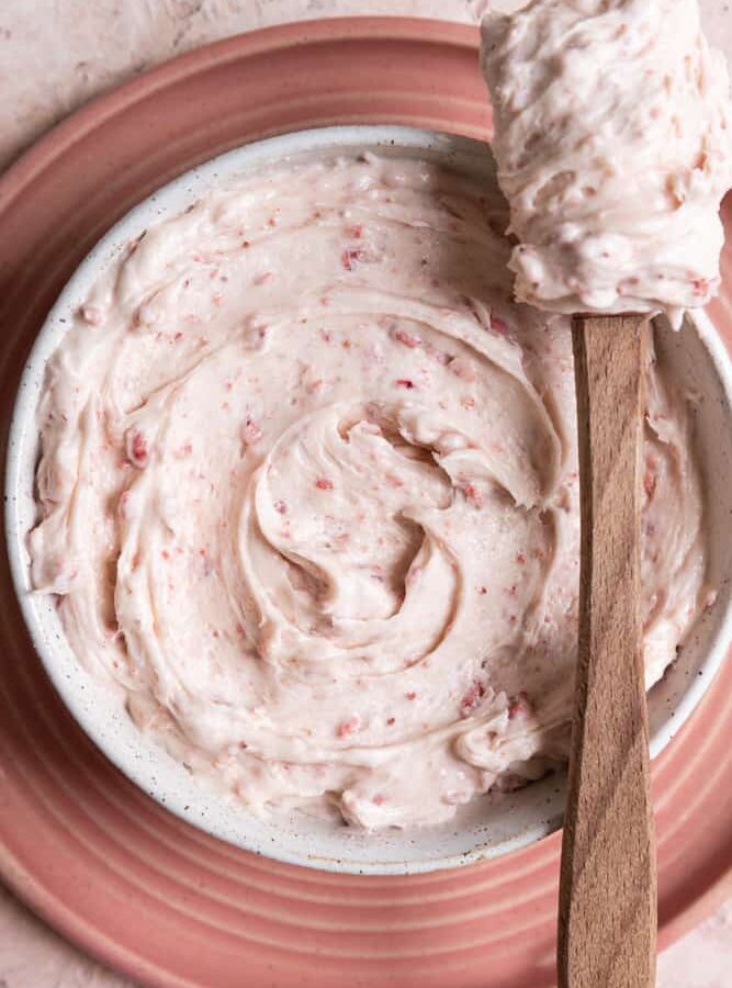 Strawberry cream cheese frosting in a white bowl.