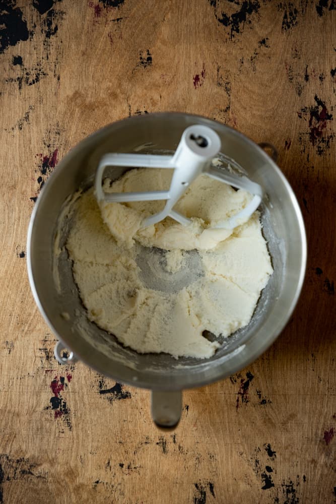 Creamed butter and sugar in a mixing bowl on a wooden surface.