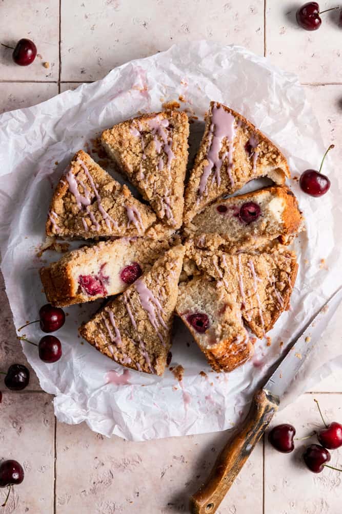A cherry coffee cake cut into slices on parchment paper. 