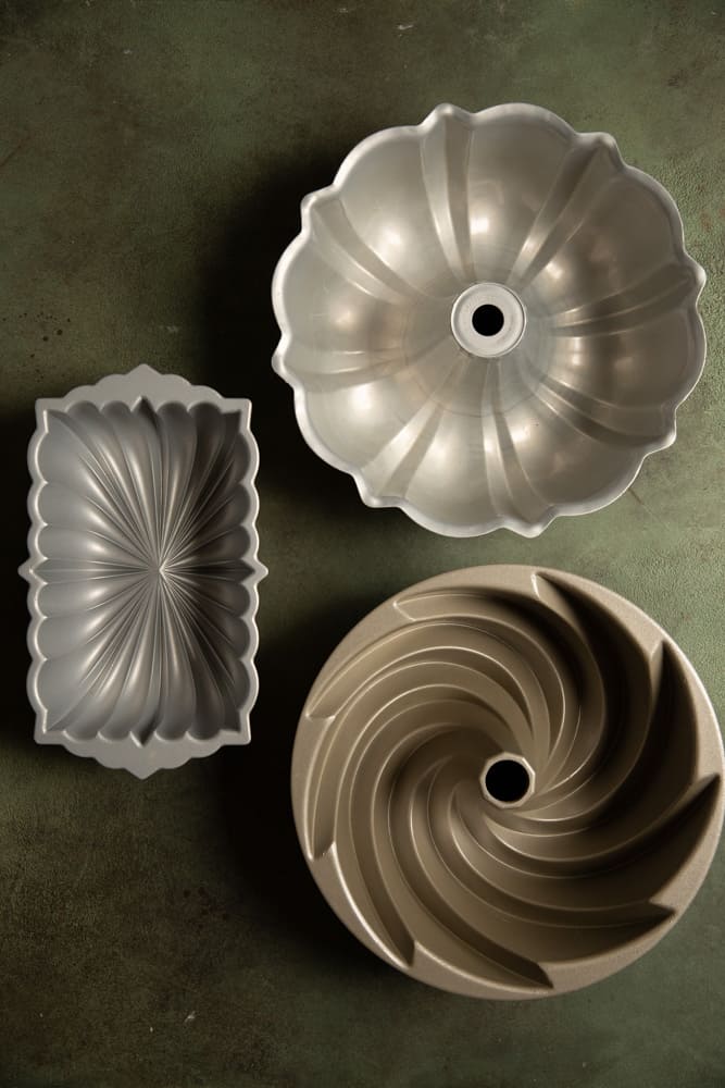 3 different kinds of bundt pans on a green surface.