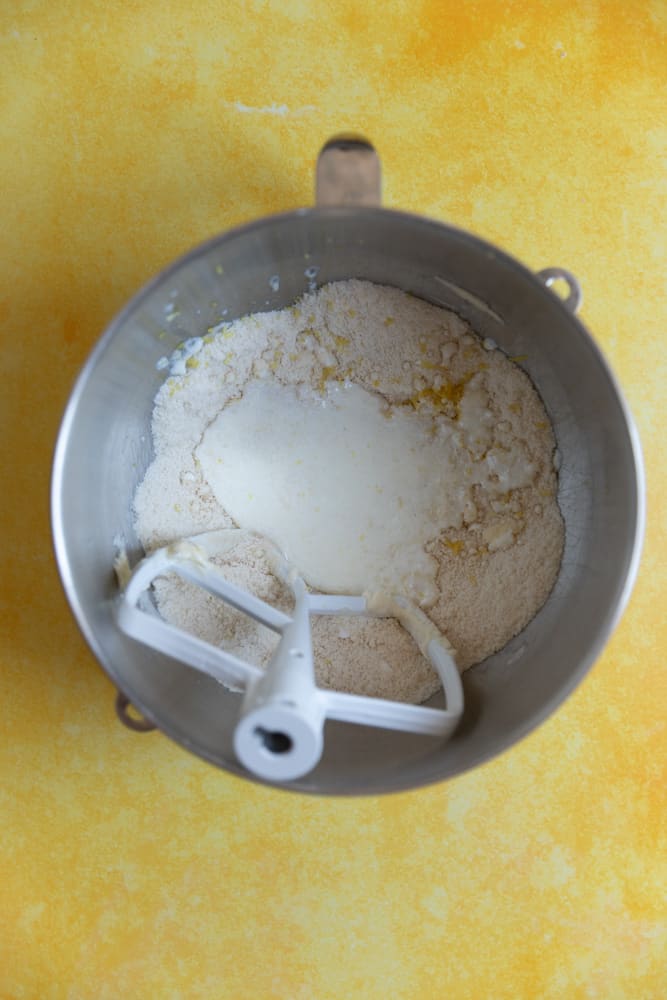 Milk added to a mixture of flour and butter in a mixing bowl. 