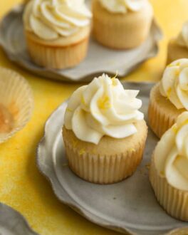 A lemon cupcake with frosting and lemon zest sitting on a gray ruffled plate.
