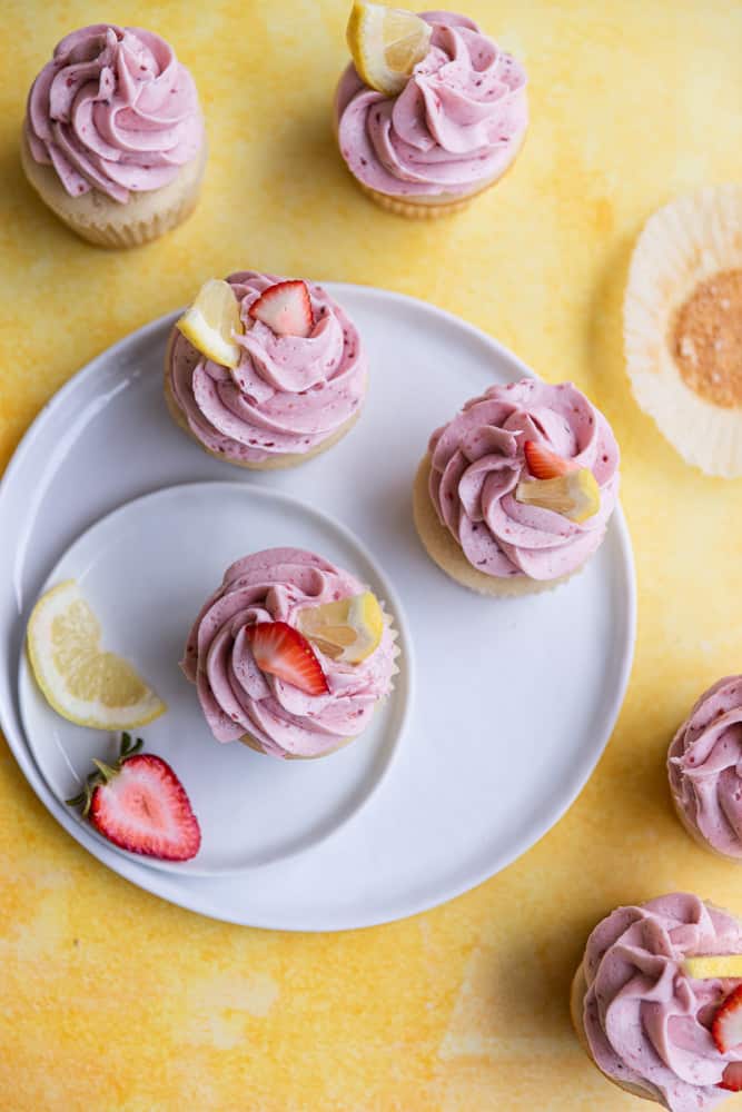Strawberry lemon cupcakes shot overhead on white overlapping plates.
