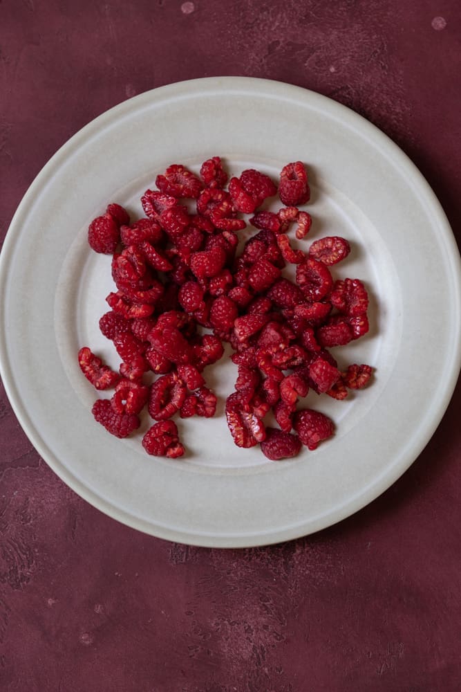 Fresh raspberries drying on a tan plate.