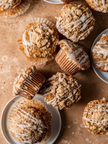 Coffee cake muffins arranged on a peach colored backdrop.