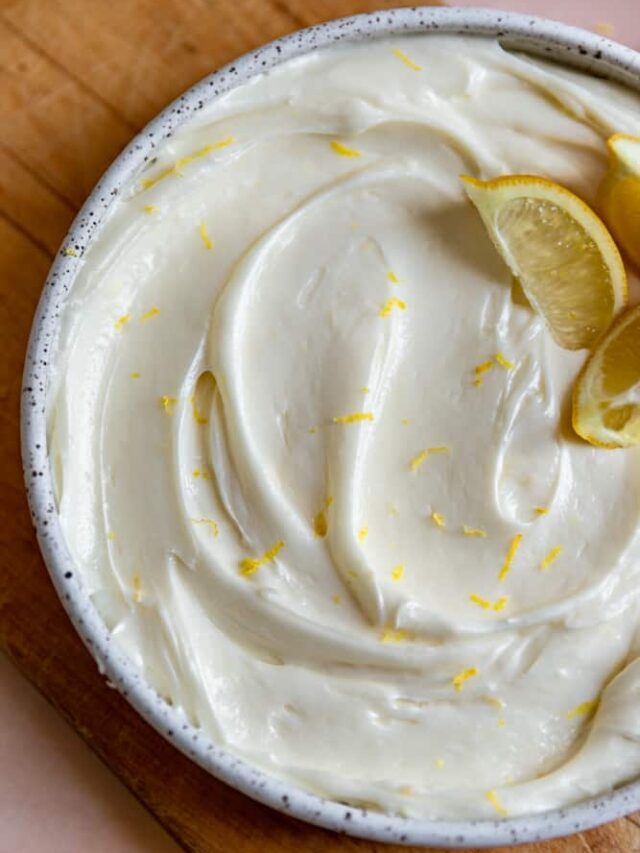 Lemon cream cheese frosting swirled into a bowl with lemon zest on top.