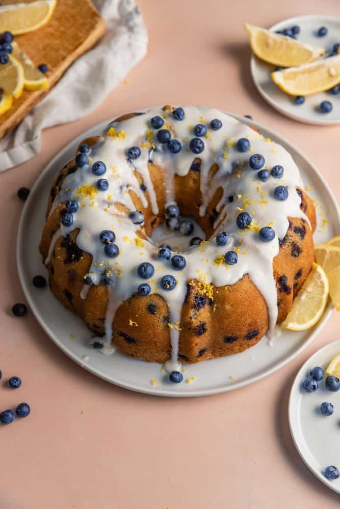  A lemon blueberry bundt cake garnished with fresh lemon zest and blueberries.