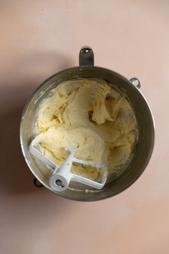 Butter, sugar, and eggs mixed together in a mixer bowl.