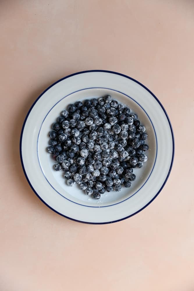 Blueberries tossed with flour in a white bowl.
